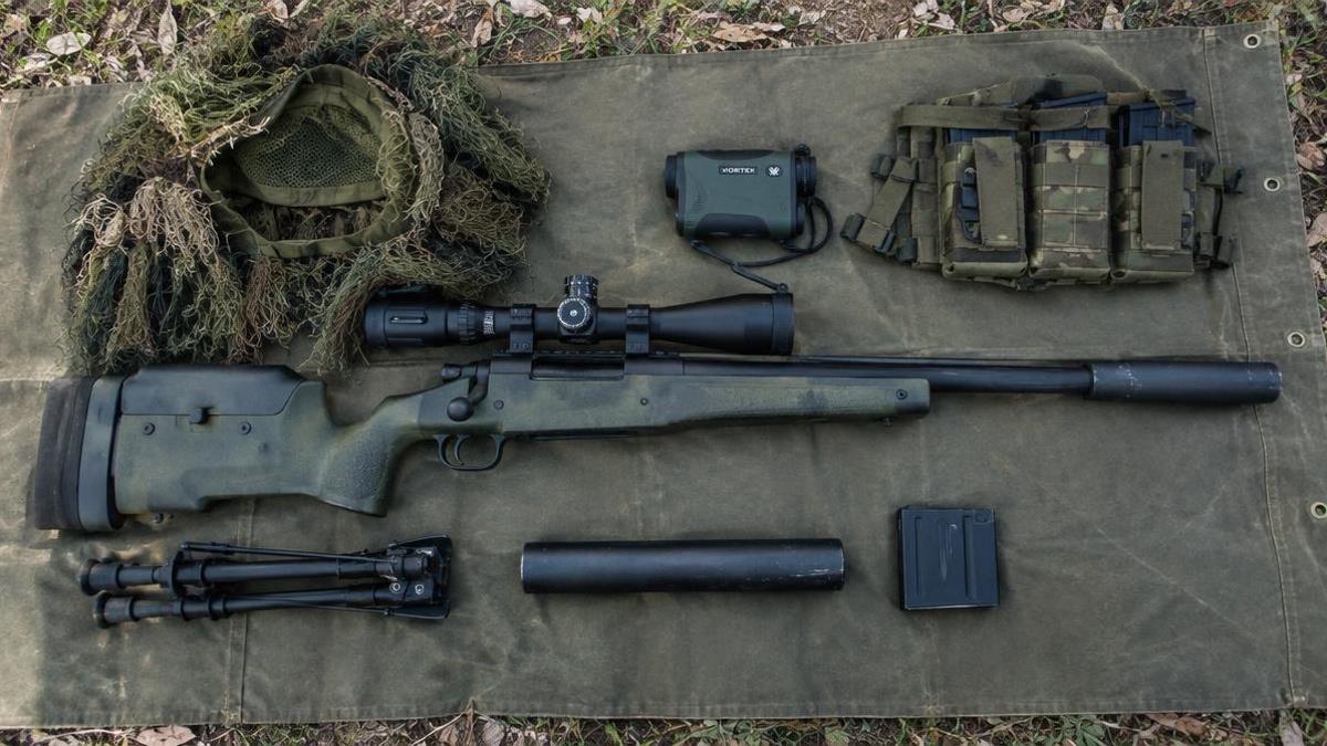 Airsoft sniper loadout accessories laid out on a canvas mat